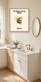 The smug bee print in an oak frame hanging above a bathroom vanity — frame for display only, not included