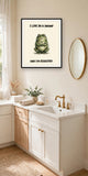 The same print shown hanging in a bathroom — frame for display only, not included